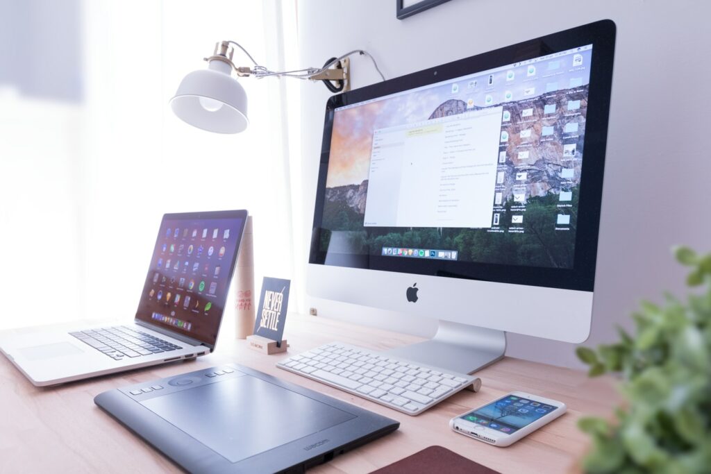 the age of consumerism silver iMac near iPhone on brown wooden table