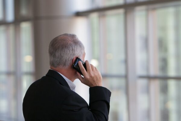 man holding black smartphone in front of a windowpane business phone system