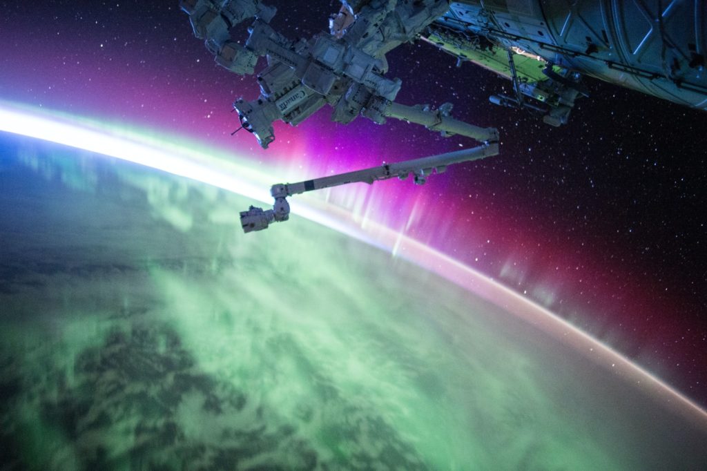 photography of purple and green aurora beam below grey space satellite starlink